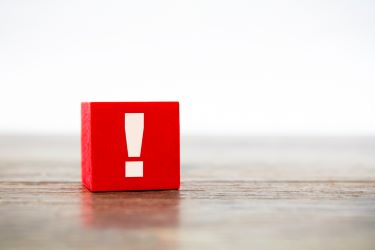 Photograph of a red square block on a table with an exclamation mark