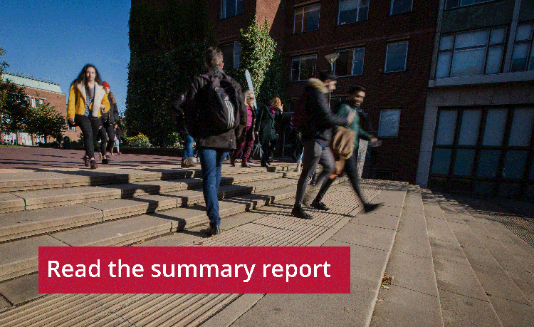 Students walking briskly across a university campus paved with rectangular blocks, with a brick building in the background. A caption overlay reads "Read the summary report." There's a sense of motion exemplified by the students having a slight blur.