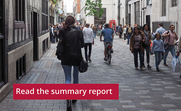 Person walking down a busy city street while capturing a photo, with other pedestrians around and a banner at the bottom saying 'Read the summary report'.